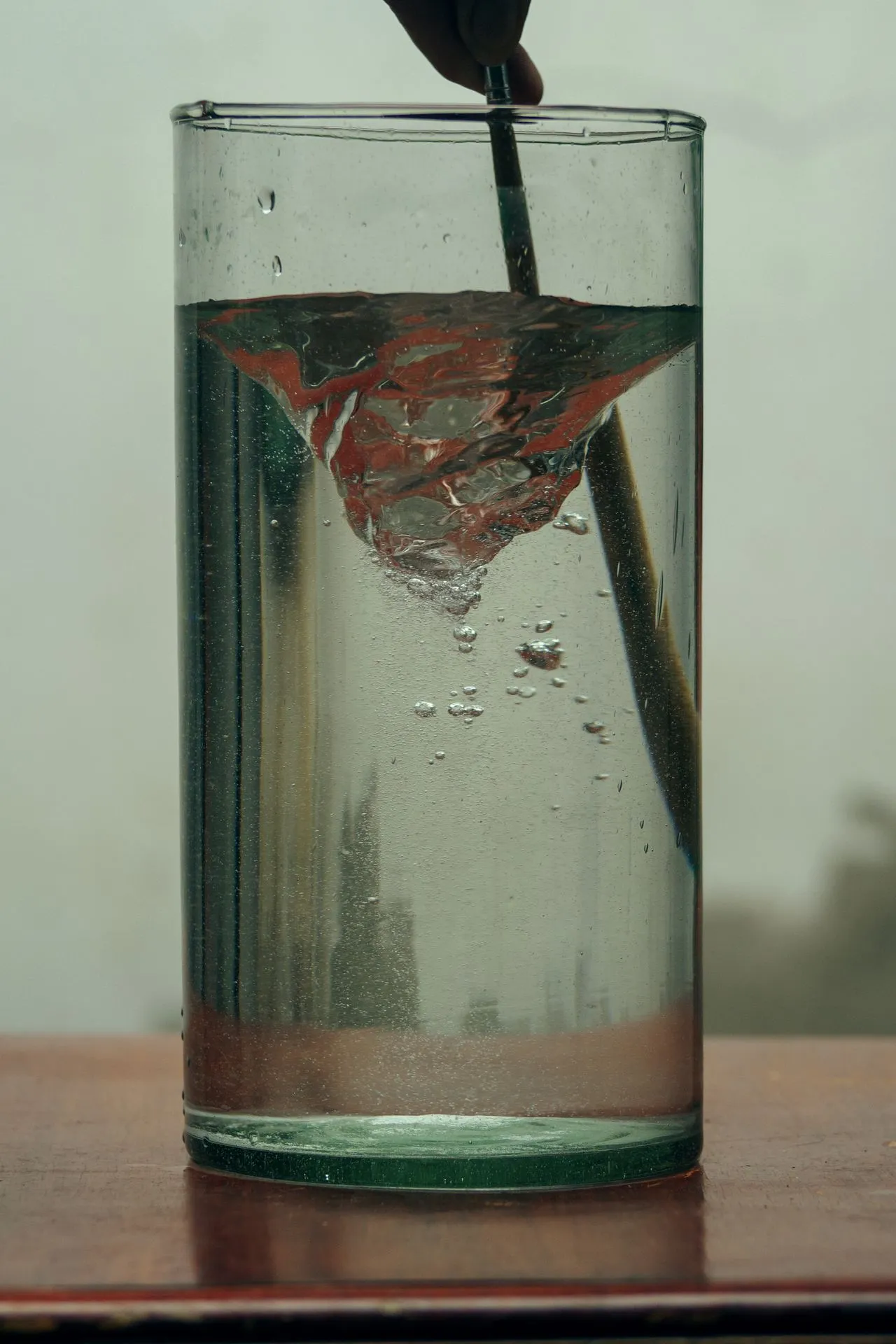 Spoon stirring a swirl into a tall glass of clear water